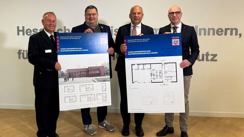 Vorstellung Handlungsempfehlung Musterfeuerwehrhaus Innenminister Poseck steht mit mehreren Personen zusammen und präsentiert die Handlungsempfehlung zum Musterfeuerwehrhaus Hessen.